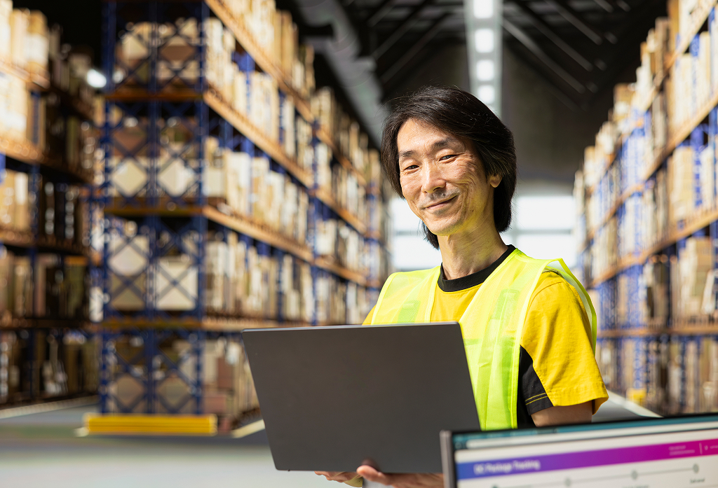 Asian man managing shipping operations at a fulfillment centre — offshore logistics role